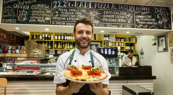 Chef sonriente en Zaragoza ofrece una pizza artesana. ¡Los soletes Repsol de esta pizzería son deliciosos!