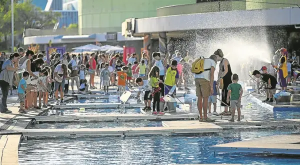 Niños y adultos disfrutan de un **espacio río y juego** con actividades acuáticas bajo el sol.