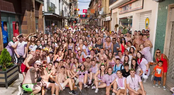 Multitud celebrando las fiestas de Zuera, con gente sonriendo y posando para la foto en una calle.