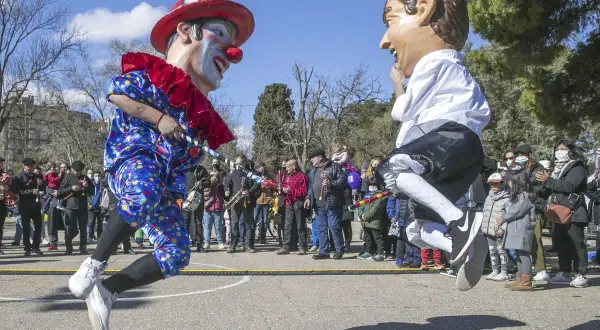 Gigantes y cabezudos saltan en una fiesta popular. Un payaso y un hombre con boina roja celebran el 5 de marzo.