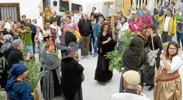 Gente celebra la fiesta de las brujas en Trasmoz. Mujeres vestidas de negro y con sombreros de bruja, rodeadas de hierbas y flores.