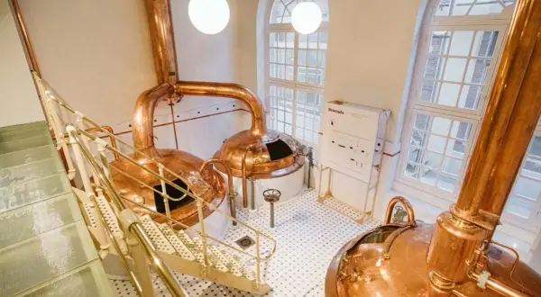 Cata de cervezas Zaragoza: Cobre brillante y escaleras metálicas en una cervecería tradicional.