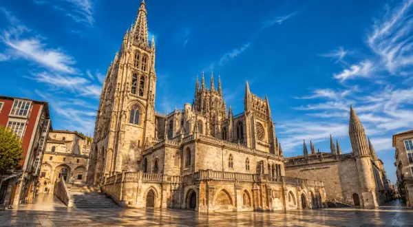 La majestuosa catedral de Burgos se alza bajo un cielo azul con nubes algodonosas.