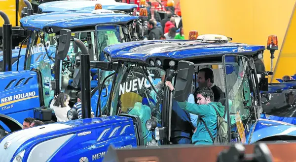 Tractores New Holland en la FIMA Zaragoza 2026. Personas observan los nuevos modelos, algunos niños curiosos se asoman.