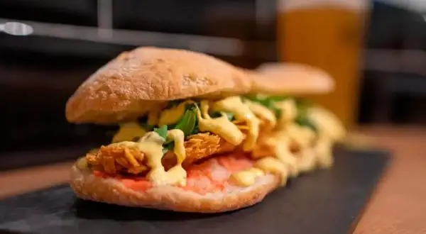 Un bocadillo generoso con pollo crujiente, salsa y rúcula, uno de los mejores bocadillos de Zaragoza.