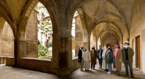 Un grupo visita el claustro del monasterio de la Resurrección en Zaragoza, admirando su arquitectura y vegetación.