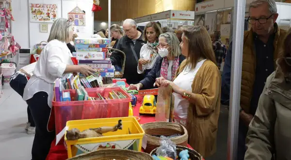 Gente comprando en un puesto de **rastrillo Aragón** con juguetes y libros.