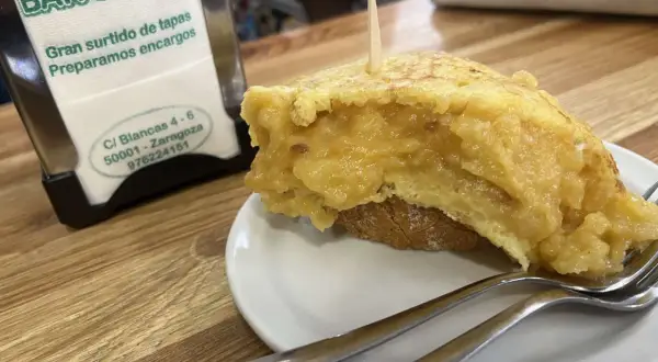 Deliciosa tortilla de patata zaragozana en Bar Circo, lista para disfrutar con tenedores.