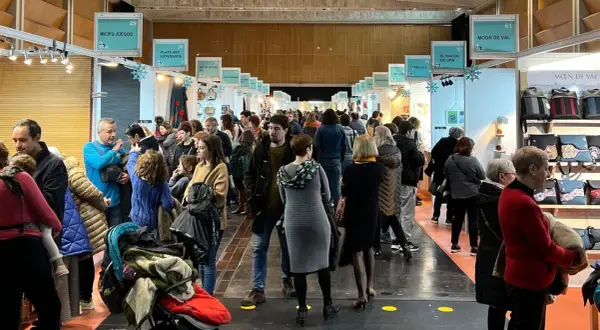 Gente disfrutando de la feria artesanía Zaragoza, con puestos de juegos, arte y bolsos.