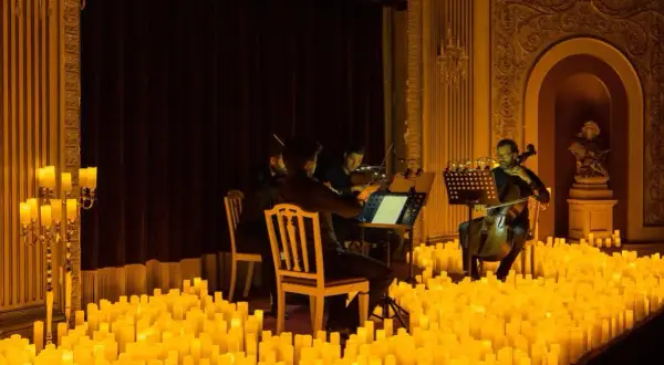 Un concierto de música clásica bajo la luz de miles de velas en Zaragoza. Músicos tocan violines y violonchelos en un escenario iluminado por velas.