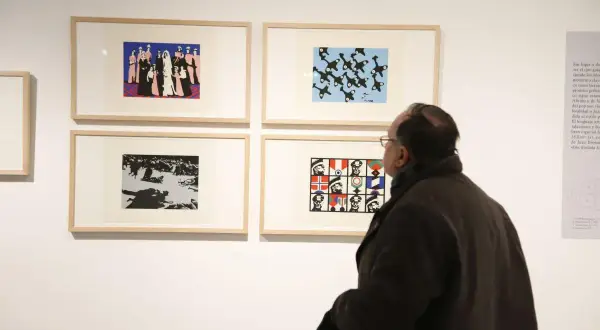 Un hombre observa obras de arte en una galería, incluyendo una que representa figuras militares y banderas, evocando el estilo de Pablo Serrano.