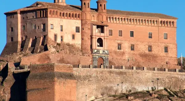 Imponente castillo Zaragoza, con sus torres y cúpulas, se alza sobre una colina rocosa, vigilando el paisaje.