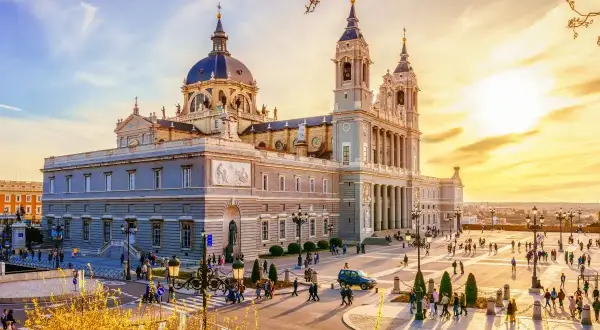 Catedral de la Almudena, uno de los **lugares para conocer en Madrid**, con gente paseando en una tarde soleada.