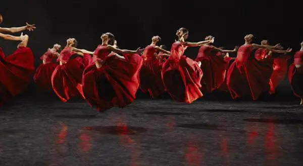 Danzarinas con vestidos rojos vibrantes en el escenario, evocando la fuerza de Carmina Burana en Zaragoza.