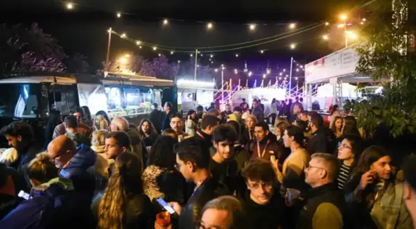 Multitud disfrutando de food trucks Zaragoza Pilares bajo luces festivas.