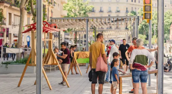 Gente disfrutando de unas vacaciones con niños en Cataluña, con juegos y actividades al aire libre en una calle peatonal.