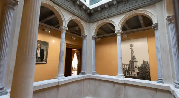 Interior del palacio de Armijo con arcos, columnas y un retrato.