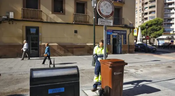 Un trabajador recoge un contenedor marrón en Zaragoza, bajo un sol radiante, como parte de la fiesta del sol.