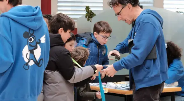 Niños observan una linterna mágica en Zaragoza, aprendiendo sobre su funcionamiento.