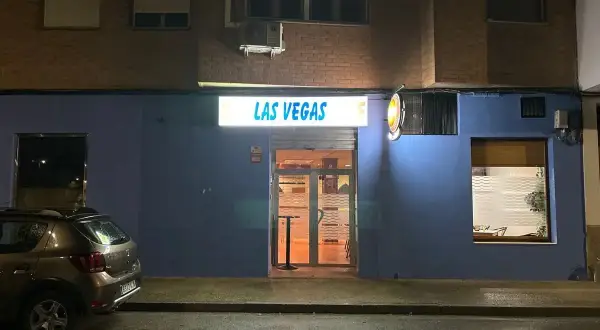 Fachada de "Las Vegas" en Zaragoza, con un coche aparcado y la calle mojada.