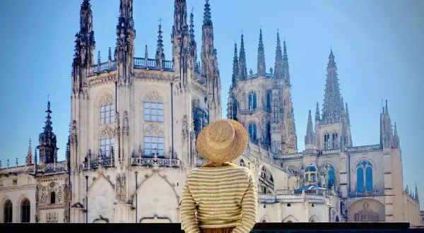 Una persona con sombrero admira la majestuosa Catedral de Burgos, considerada por muchos la mejor catedral de España, con sus imponentes agujas y detalles góticos.