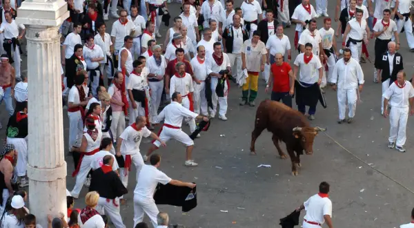Multitud en el programa fiestas Teruel, con un toro bravo y gente vestida de blanco y rojo.