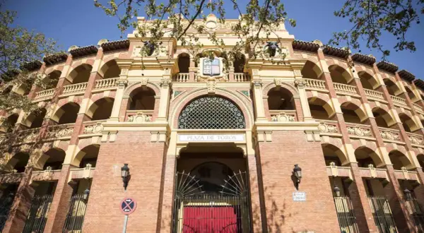 La imponente fachada de la plaza de toros de Zaragoza, con sus arcos y balcones, se alza bajo un cielo azul.