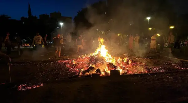 Gente reunida alrededor de una gran hoguera en Zaragoza, celebrando las hogueras de San Juan.
