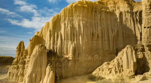 Formaciones rocosas erosionadas que recuerdan a la **Capadocia aragonesa** bajo un cielo azul con nubes.