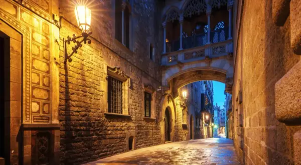 Calle empedrada y húmeda bajo un puente gótico iluminado, un rincón de los secret places Barcelona.