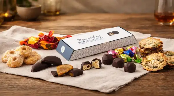 Deliciosos dulces de Aragón: bombones, galletas y caramelos envueltos en papel brillante, junto a una caja de "Moscatelicos" de Manuel Segura.