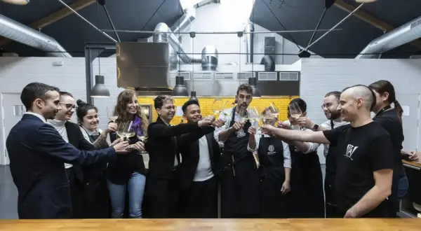 Equipo brindando con copas de vino en una cocina profesional, celebrando el éxito culinario que podría llevar a estrellas Michelin Zaragoza.