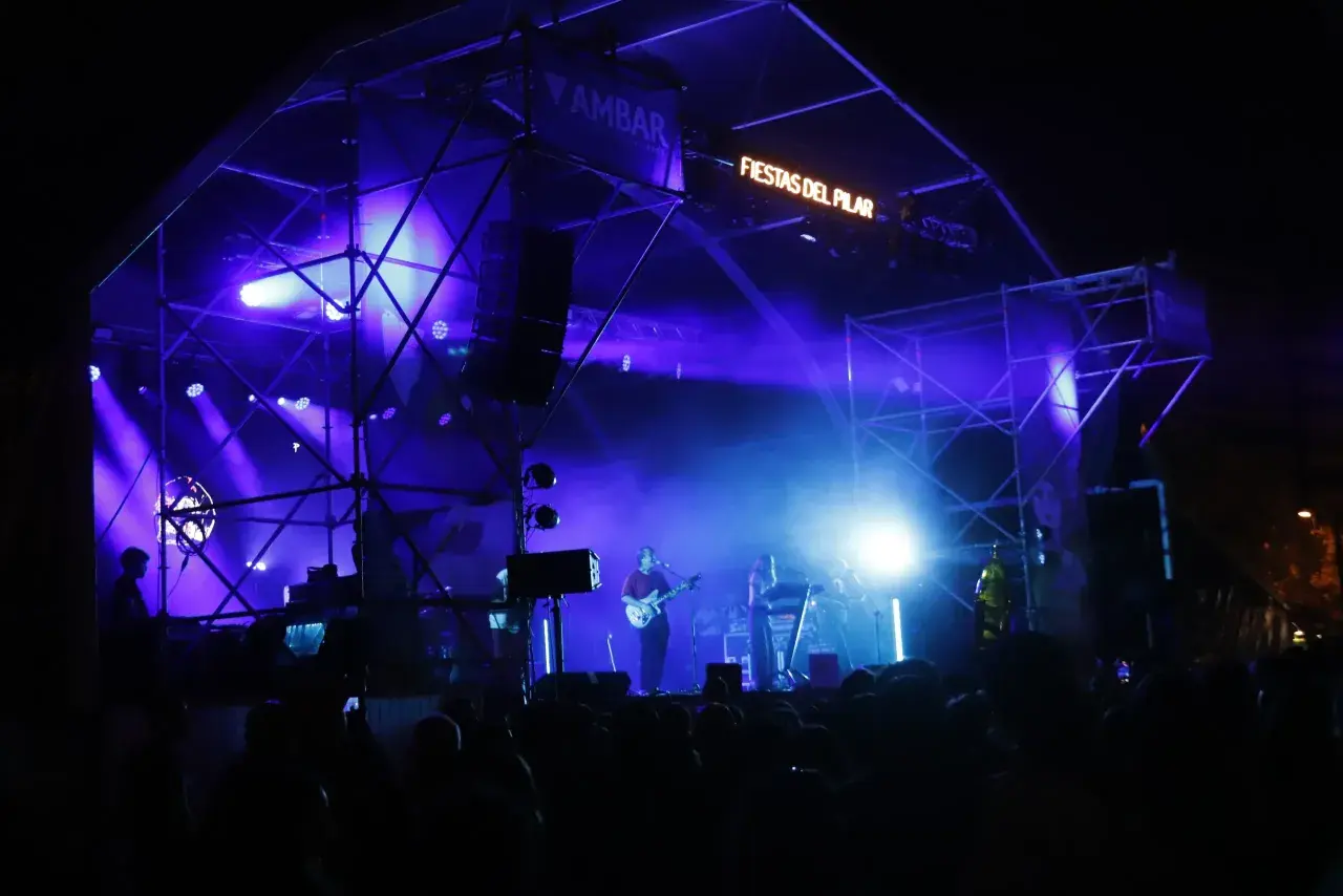 Escenario iluminado con luces azules para un concierto en la Estación del Norte de Zaragoza durante las Fiestas del Pilar.