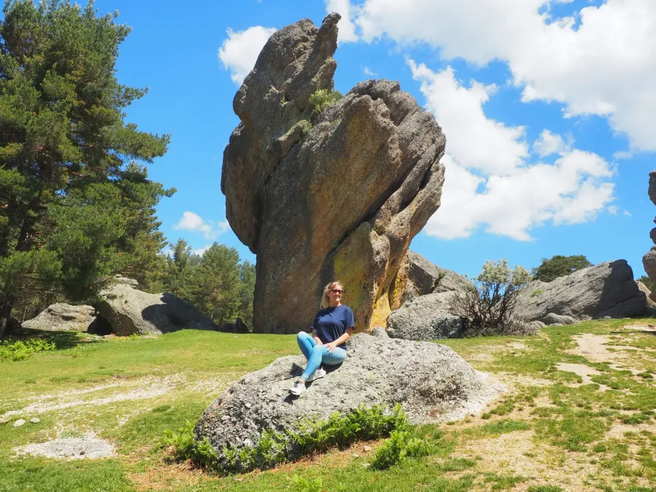 Mujer sentada en roca, con imponente formación rocosa detrás. Un paisaje natural que demuestra que merece la pena visitar Soria.