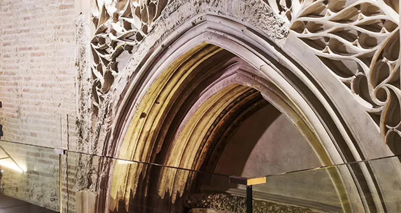 Detalle arquitectónico de un arco gótico en el museo Alma Mater, con ladrillo expuesto y ornamentación de piedra calada.