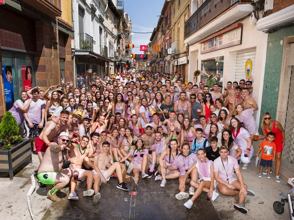 Multitud celebrando las fiestas de Zuera, con gente sonriendo y posando para la foto en una calle.