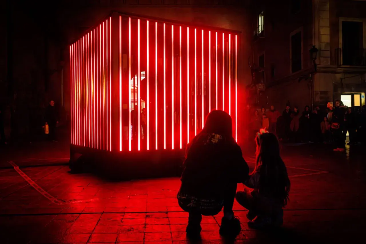 Dos personas observan una instalación de luces rojas en Zaragoza, un adelanto de lo que Zaragoza luce 2026.