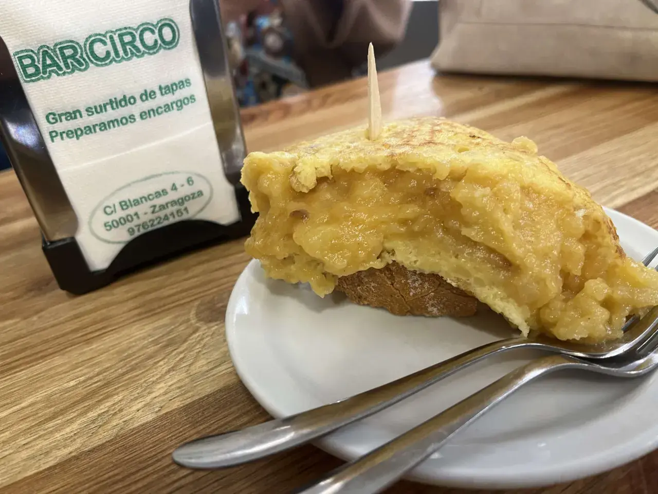 Deliciosa tortilla de patata zaragozana en Bar Circo, lista para disfrutar con tenedores.