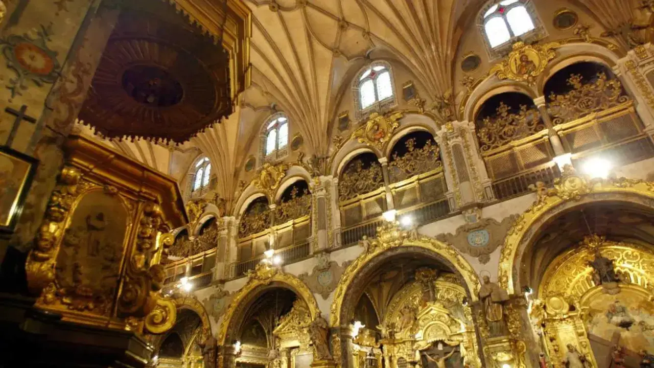 Interior del real seminario de San Carlos, con altares dorados, arcos ornamentados y techos abovedados.