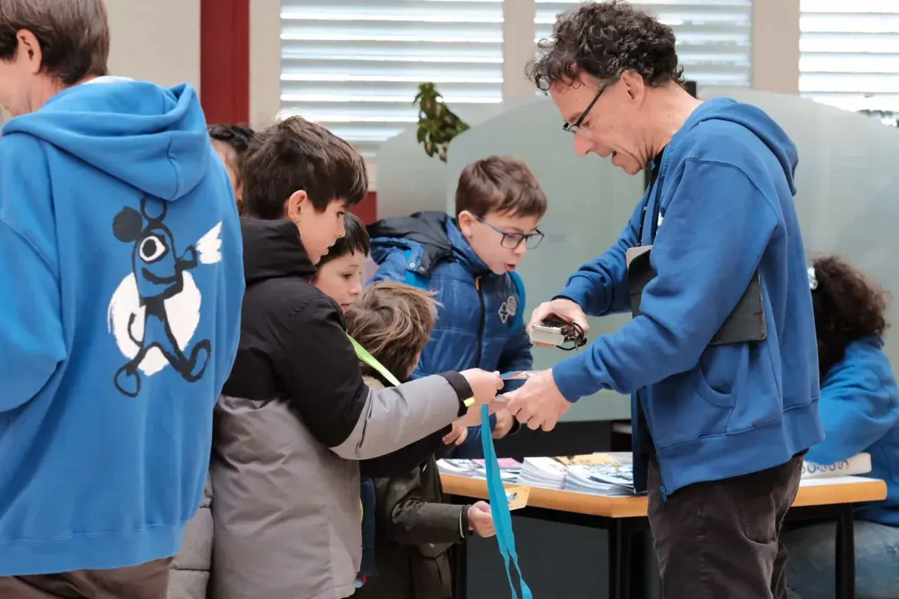 Niños observan una linterna mágica en Zaragoza, aprendiendo sobre su funcionamiento.