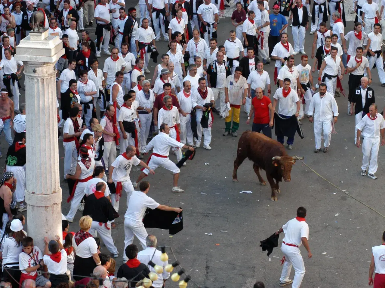 Multitud en el programa fiestas Teruel, con un toro bravo y gente vestida de blanco y rojo.