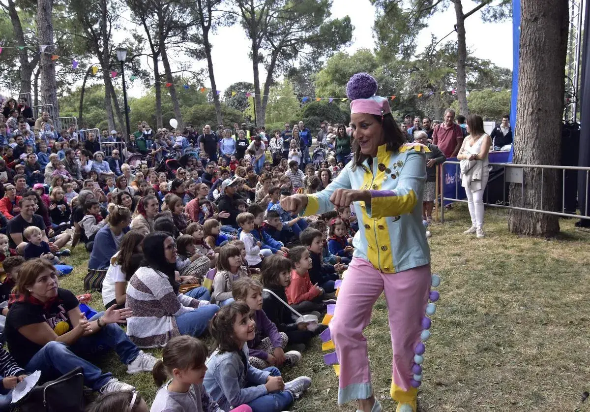 Actriz con traje colorido anima a niños en un espectáculo de marionetas en el parque.