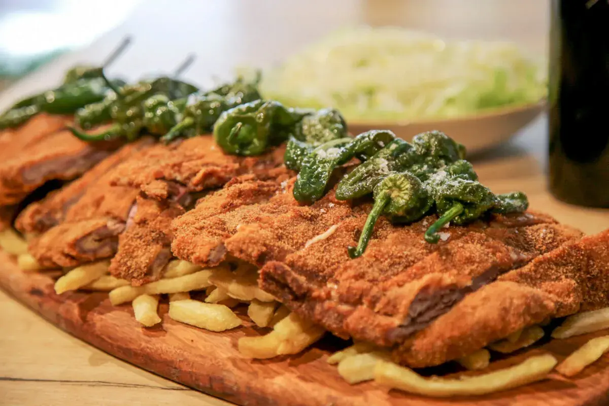 Un festín de cachopo crujiente, patatas fritas doradas y pimientos de Padrón. ¡Una delicia para compartir!