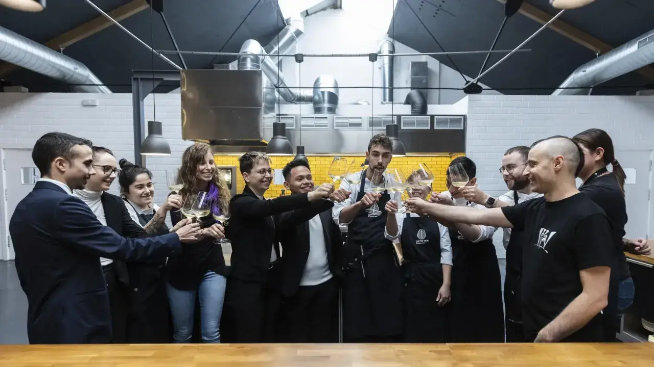 Equipo brindando con copas de vino en una cocina profesional, celebrando el éxito culinario que podría llevar a estrellas Michelin Zaragoza.