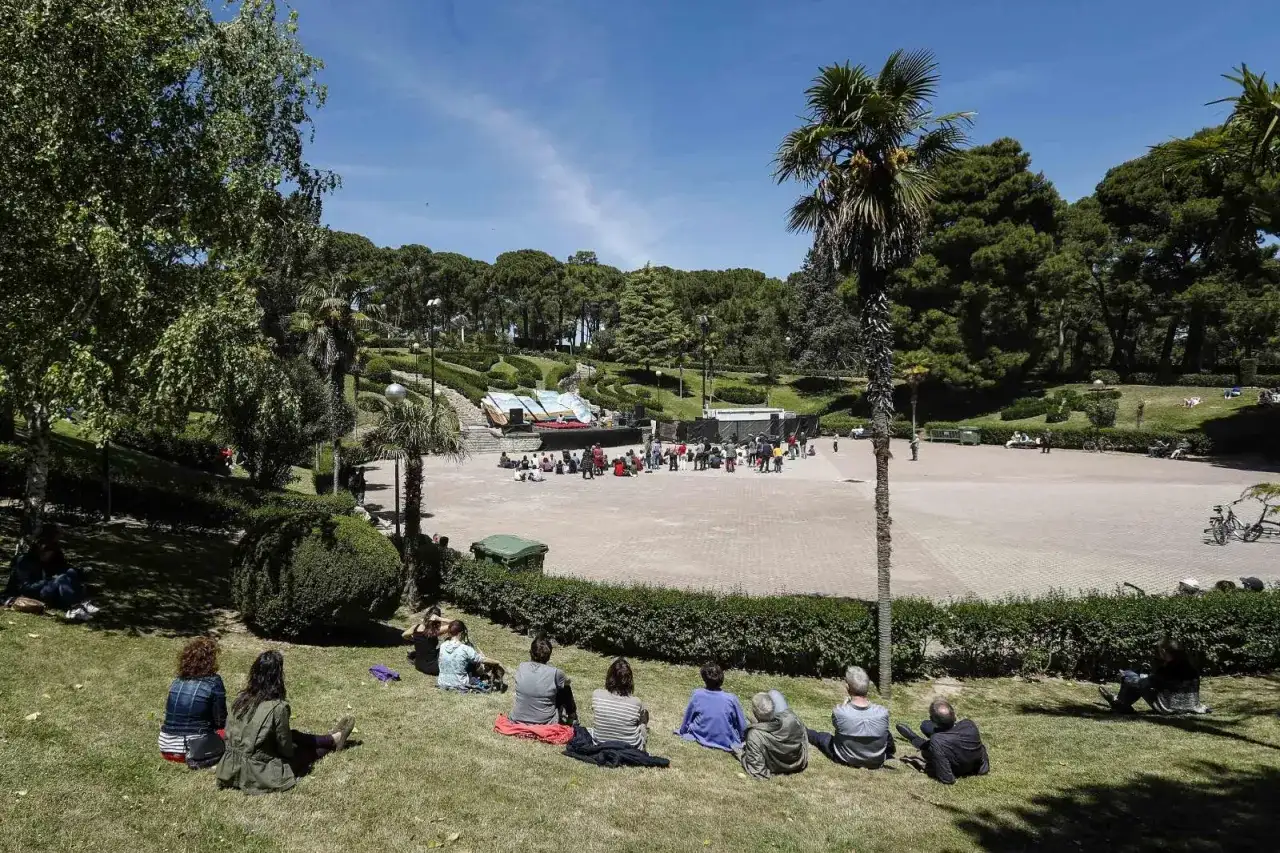 Gente sentada en el césped y en una plaza, disfrutando de un día soleado en el **jardín de invierno Zaragoza**.