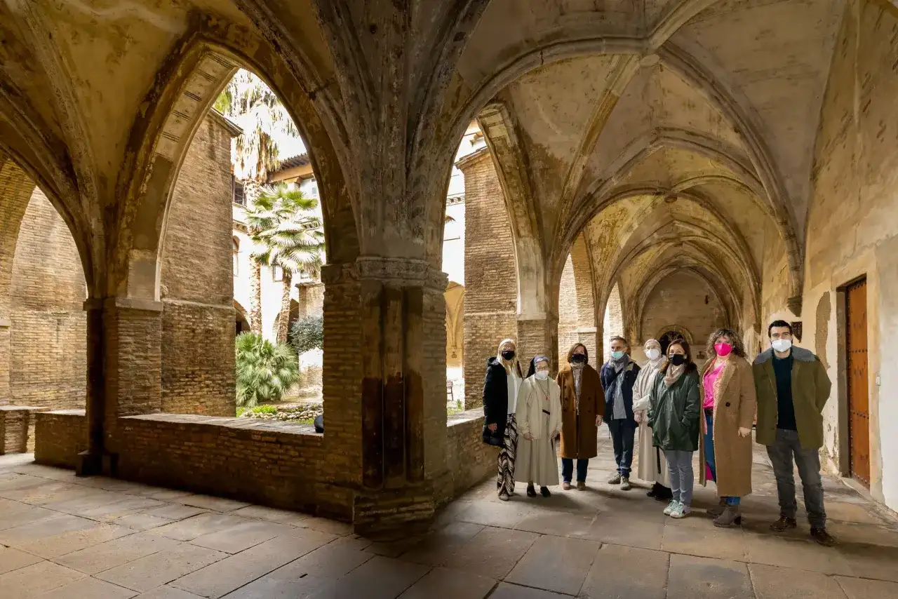 Un grupo visita el claustro del monasterio de la Resurrección en Zaragoza, admirando su arquitectura y vegetación.