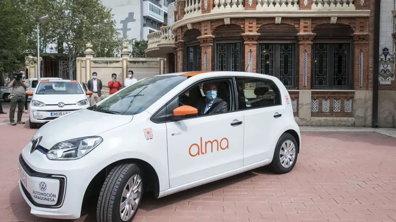 Un hombre con mascarilla conduce un coche blanco de carsharing en Zaragoza.
