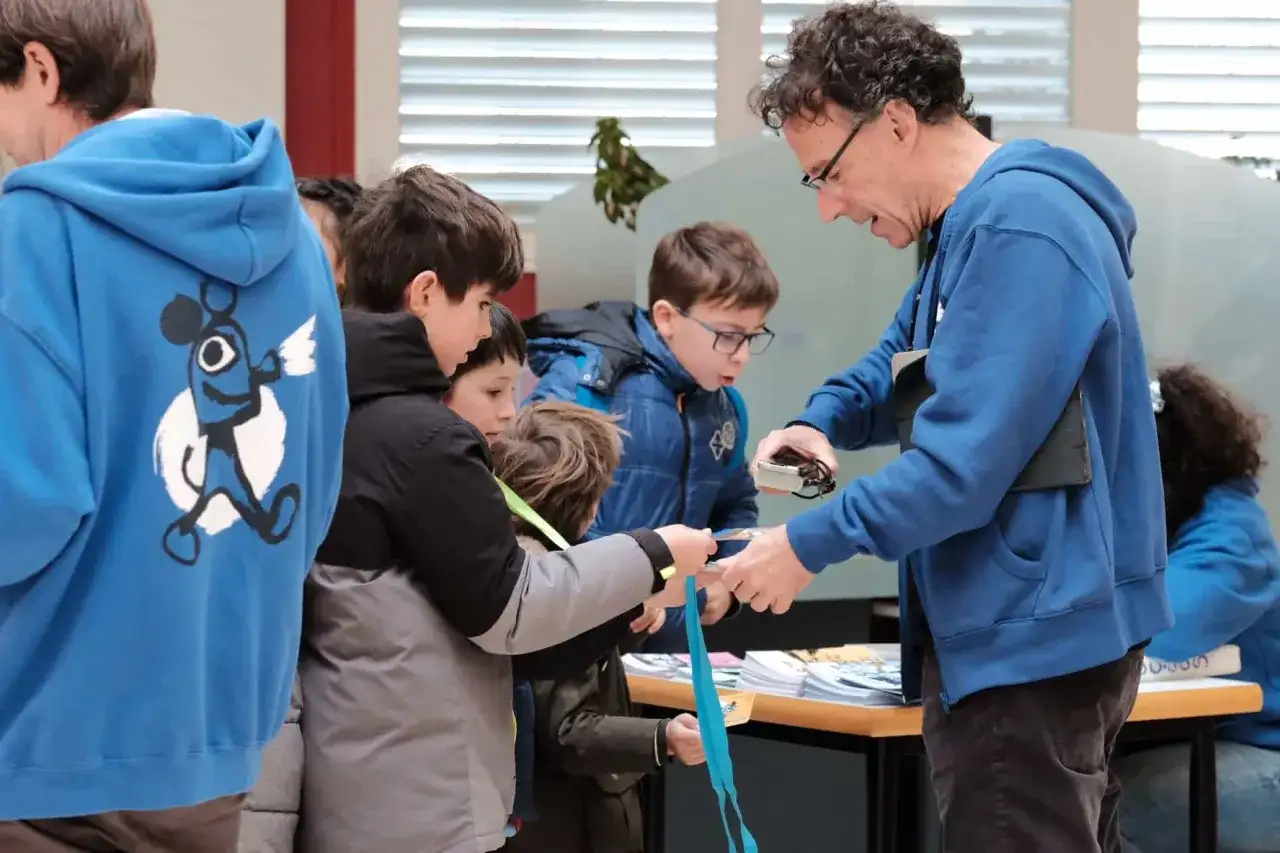 Niños observan una linterna mágica en Zaragoza, aprendiendo sobre su funcionamiento.