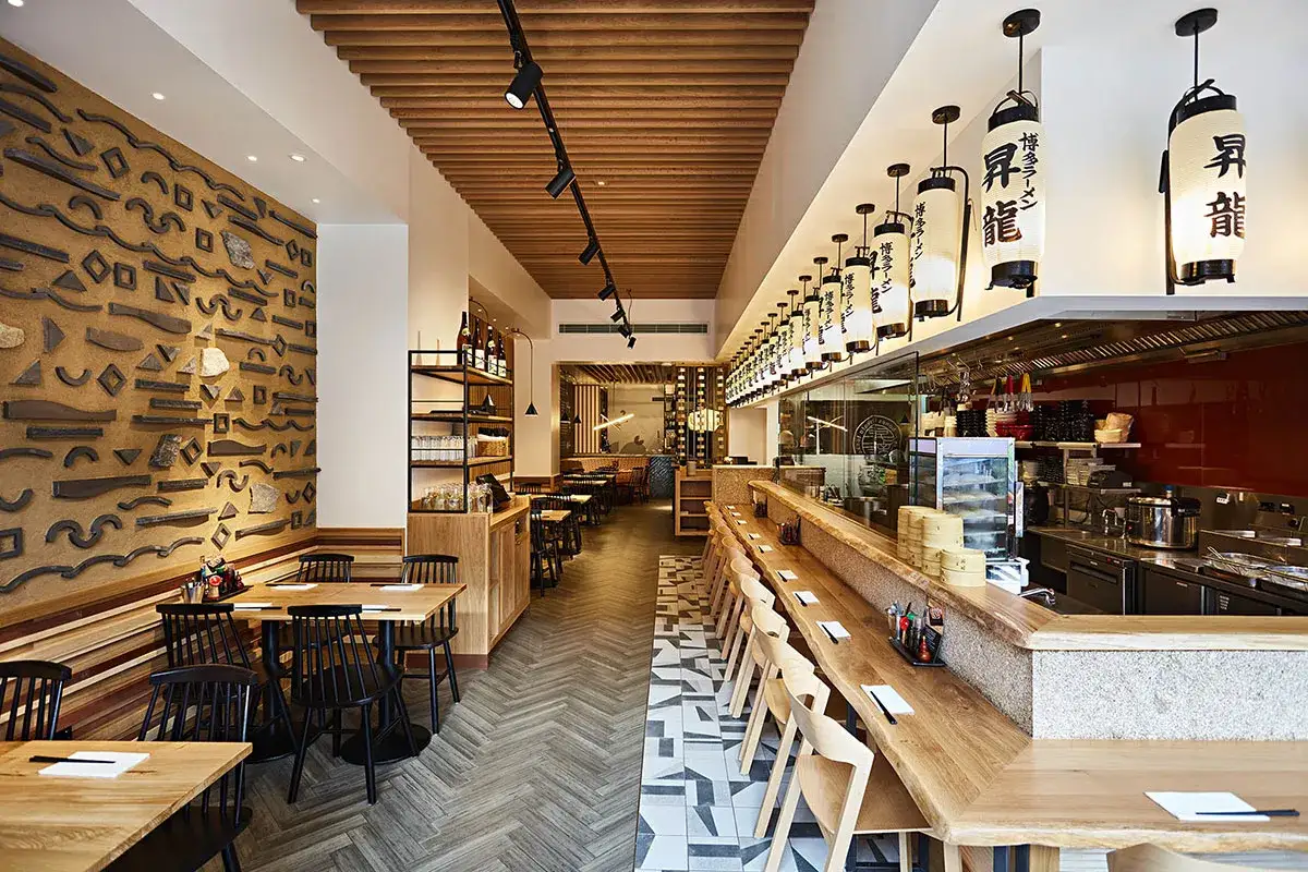 Interior de restaurante de ramen en Zaragoza, con decoración de pared texturizada, lámparas japonesas y barra de madera.