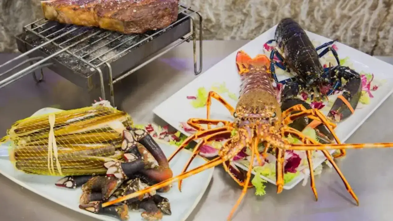 Delicioso marisco Zaragoza: langosta, navajas y percebes listos para cocinar junto a un jugoso filete a la parrilla.